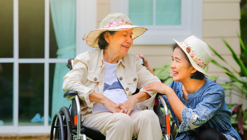 woman and old lady in wheelchair smiling