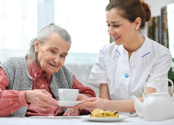 caregiver giving senior woman a cup of tea